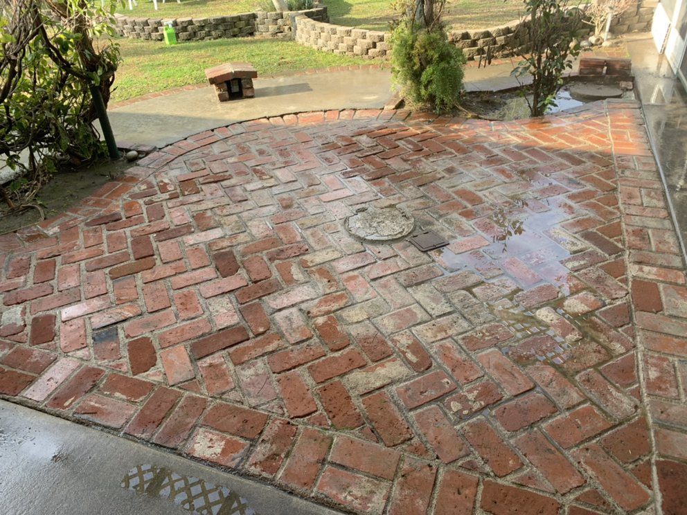 Pressure washing a concrete driveway with a bright clean stripe against dirty concrete